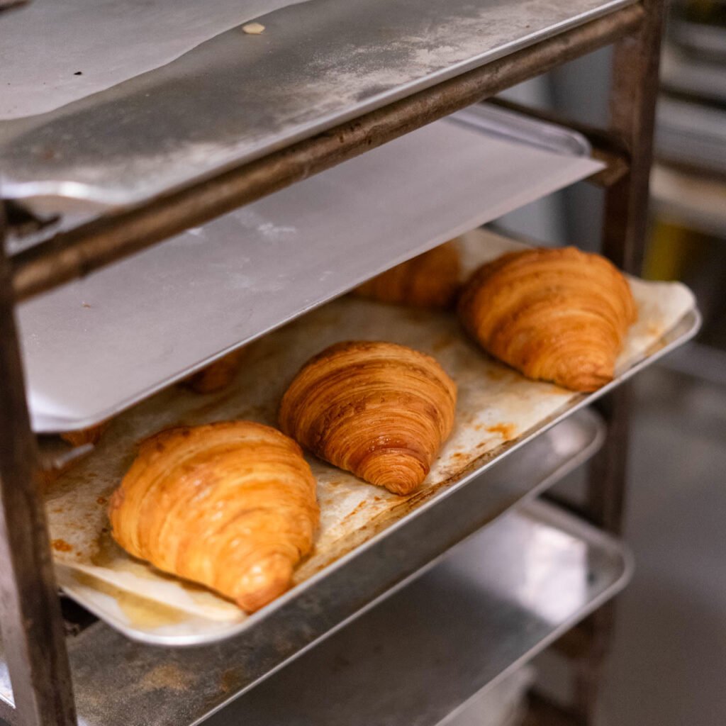 Croissants recién horneados en el carro del obrador