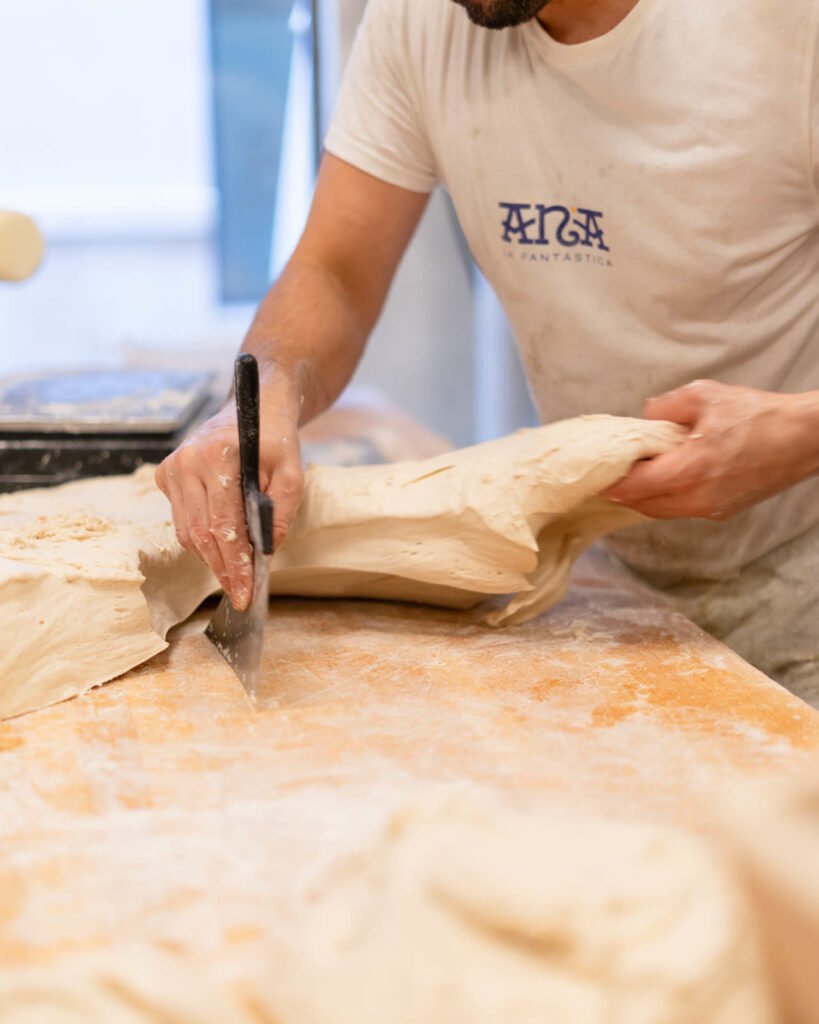Cortando la masa con la rasqueta sobre la mesa de madera